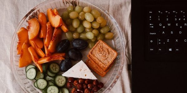 A delightful snack plate with fruits, cheese, and a laptop for a healthy lifestyle.