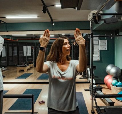 Pilates instructor guiding two women during a workout in a modern gym environment.